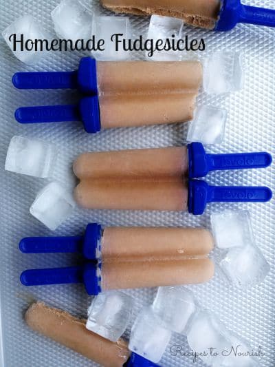 Homemade chocolate popsicles on a tray with ice.