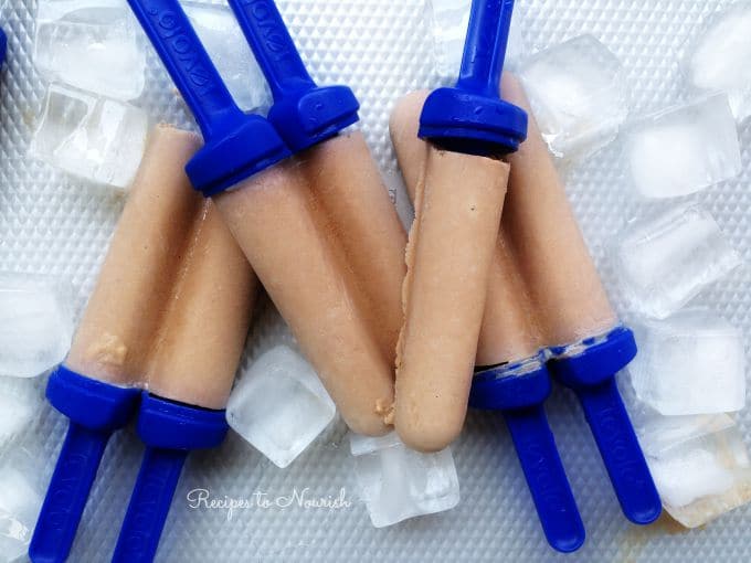 Homemade chocolate popsicles on a tray with ice.