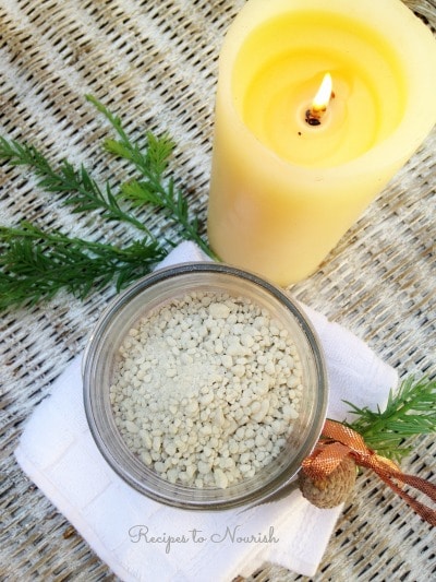 DIY bath salts next to a burning candle. 