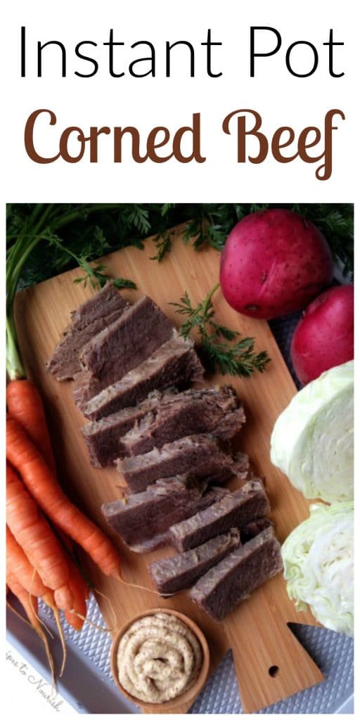 Slices of corned beef on a cutting board with carrots, cabbage and red potatoes.