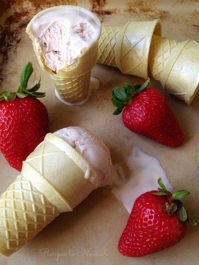 Strawberry ice cream in ice cream cones with fresh strawberries.