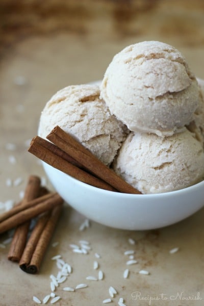 Scoops of ice cream in a bowl with cinnamon sticks and white rice around it.