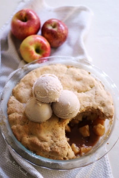 Apple cobbler topped with scoops of ice cream.