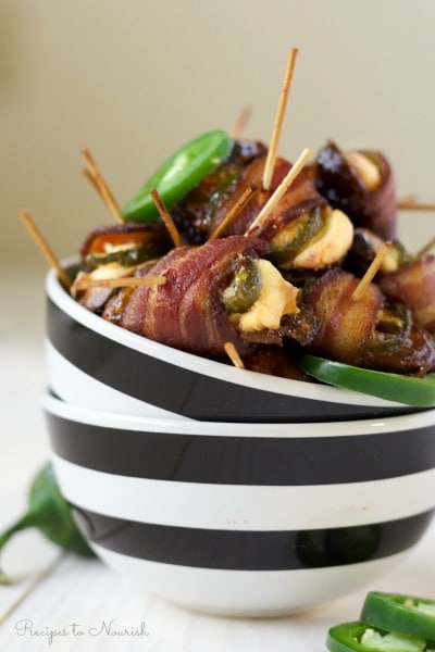 Bowl of bacon wrapped stuffed dates with cream cheese and jalapeño slices.