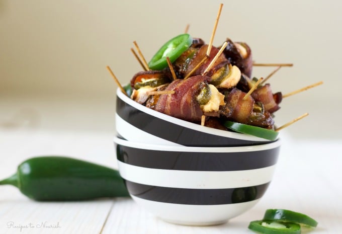 Bowl of stuffed bacon wrapped dates with cream cheese and jalapeño slices.