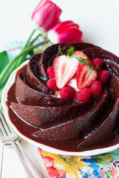 Chocolate cake made in a bundt swirl, topped with chocolate glaze and fresh berries.