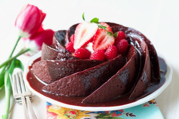 Chocolate cake in a spiral bundt shape, topped with chocolate glaze and fresh berries.