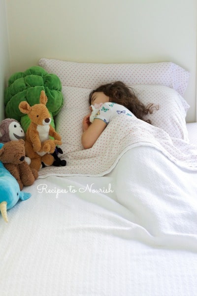 Little girl sleeping in her bed with stuffed animals.