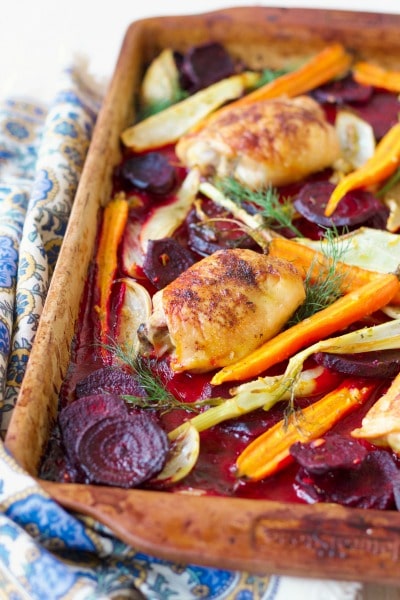 Roasted chicken thighs on a pan with roasted beets, carrots and fennel.