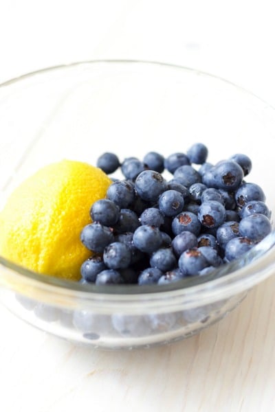 Fresh whole lemon and blueberries in a bowl.