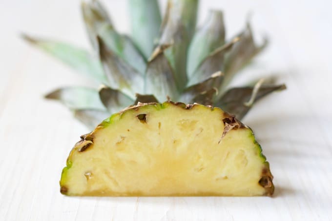 Fresh pineapple top cut in half lying flat. 
