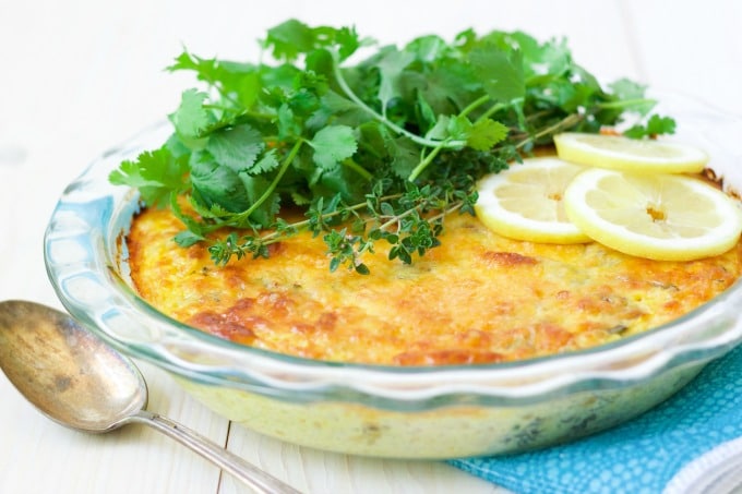 Breakfast casserole topped with fresh herbs and lemon slices. 