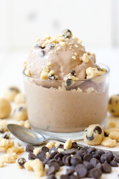Scoops of chocolate cookie dough ice cream in a bowl with cookie dough and chocolate chip crumbles on top.