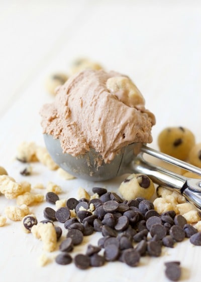 Large ice cream scoop full of chocolate cookie dough ice cream with bites of cookie dough and chocolate chips around it.
