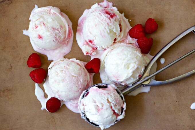 Scoops of raspberry swirl frozen yogurt with fresh raspberries.