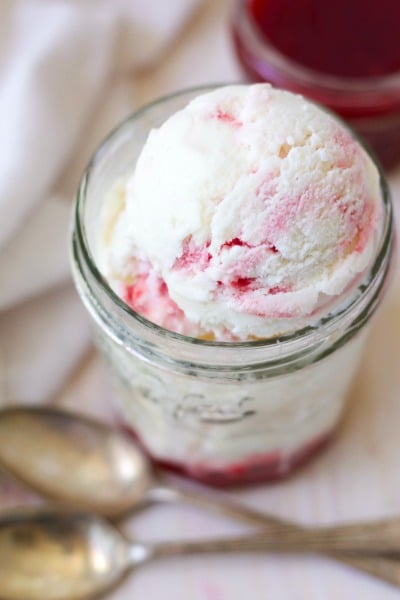 Jar of raspberry swirl frozen yogurt with raspberry sauce.
