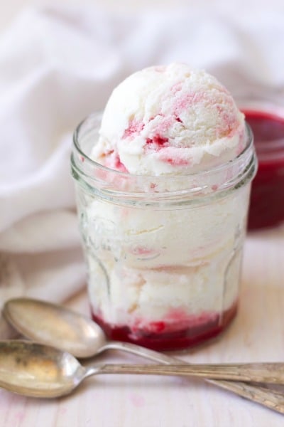 Scoops of raspberry swirl frozen yogurt with raspberry sauce in a jar.