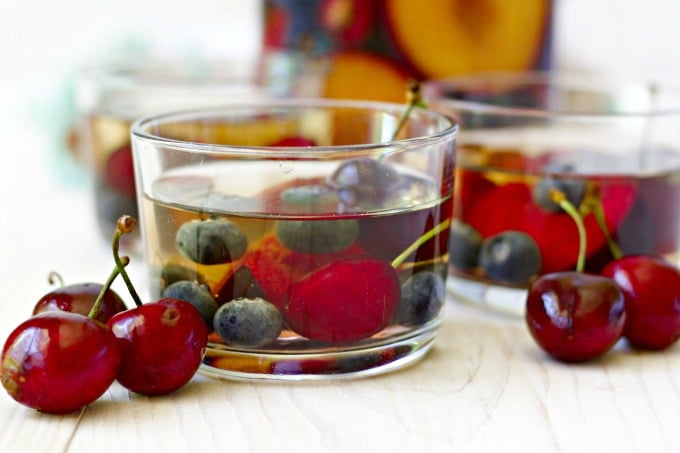 Glasses full of herbal tea sangria with stone fruit and berries.