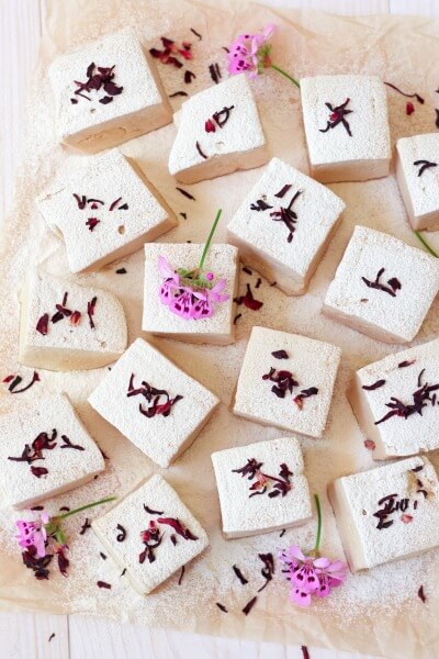 Lots of square cut homemade marshmallows with hibiscus blossoms.