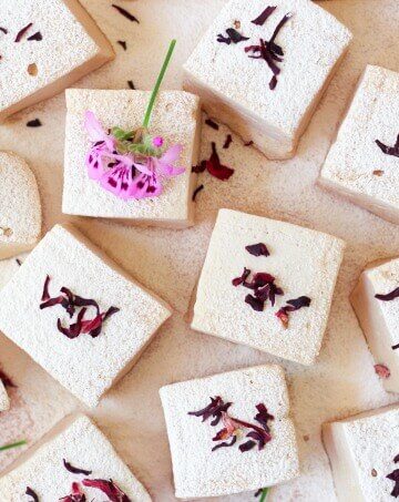 Square-cut homemade marshmallows with dried hibiscus and pink flowers.