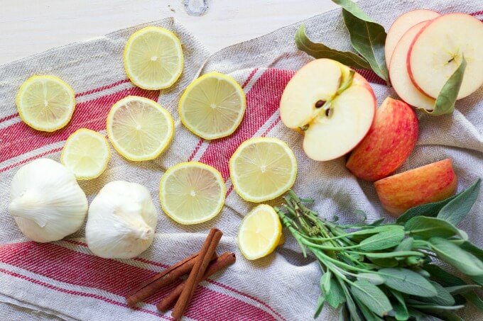 Sliced apples, lemon slices, garlic bulbs, cinnamon sticks and fresh sage and herbs.