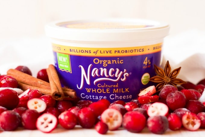 Nancy's organic whole milk cottage cheese container surrounded by cranberries and cinnamon sticks.
