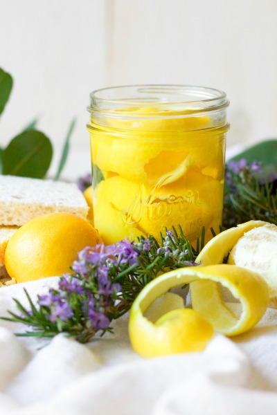 Lemon peels in a mason jar, fresh rosemary, fresh lemons, fresh leaves and kitchen dish sponges.