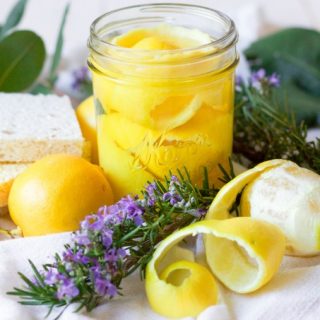 Lemon peels in a mason jar, fresh lemons, fresh rosemary, fresh leaves and kitchen dish sponges.