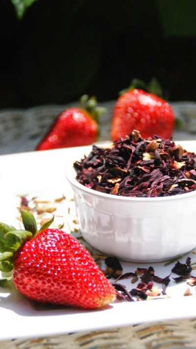 Dried hibiscus in a bowl with fresh strawberries.