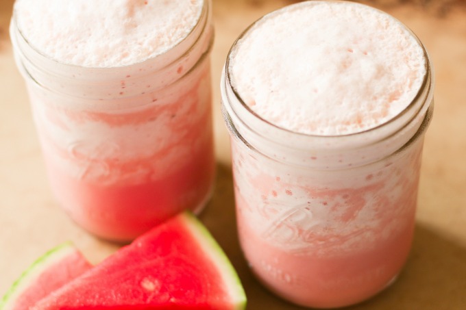 Watermelon milkshakes in 2 mason jars with fresh watermelon slices.