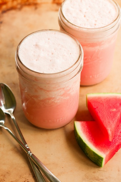 Watermelon milkshakes in 2 mason jars with fresh watermelon slices.