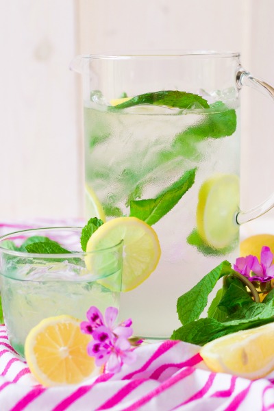 Iced mint lemonade in a pitcher and glass with fresh lemon slices and mint.