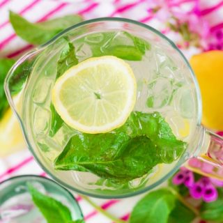 Mint lemonade over ice in a pitcher with fresh lemon slices and mint.