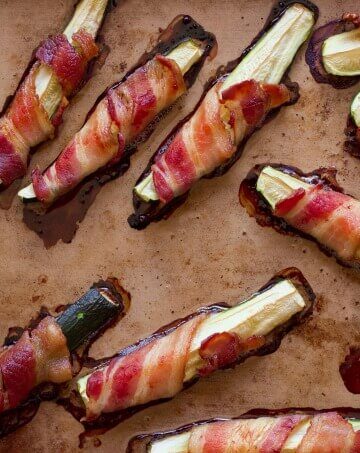 Bacon wrapped zucchini on a baking pan.
