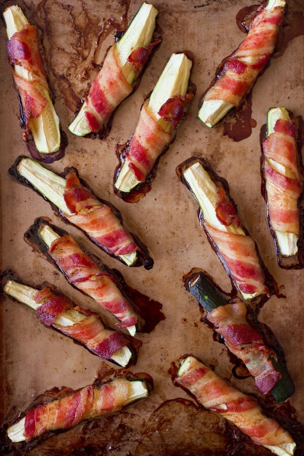 Bacon wrapped zucchini on a baking pan.