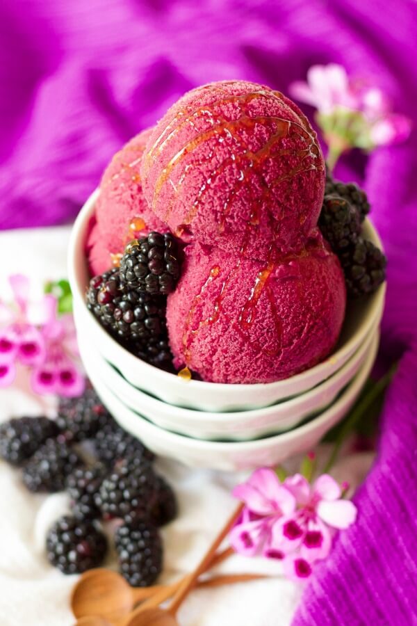 Bowl full of blackberry ice cream, fresh blackberries and drizzled with honey.