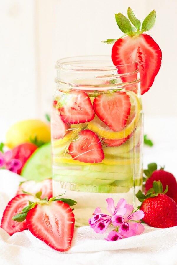 Mason jar filled with water, strawberries, lemon slices and cucumber slices.