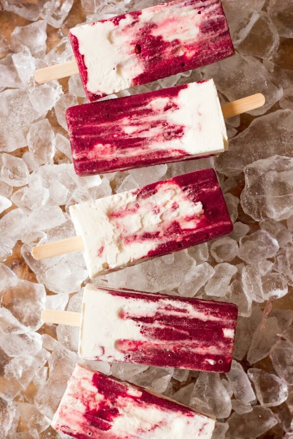 Marbled cherry and vanilla creamsicle popsicles on ice.