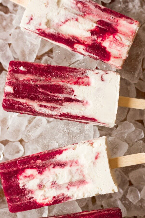 Marbled cherry and vanilla creamsicle popsicles on ice.