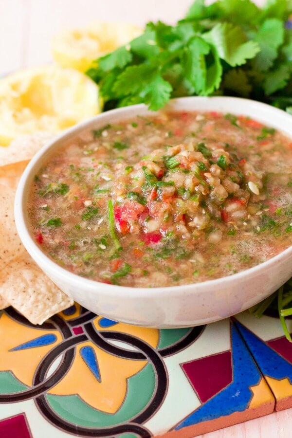 Large bowl of chunky blender salsa surrounded by chips, cilantro and juiced lemons.