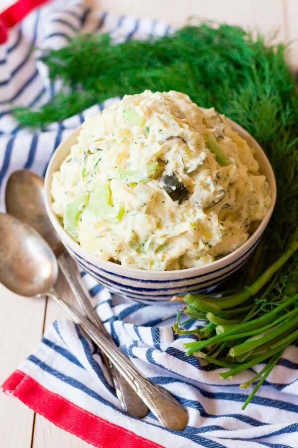 Bowl of potato salad surrounded by fresh dill.