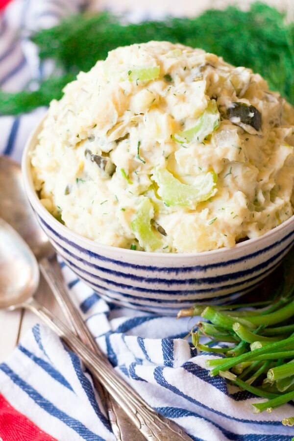 Bowl of potato salad surrounded by fresh dill.