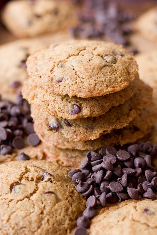 Stacks of chocolate chip cookies surrounded by chocolate chips.