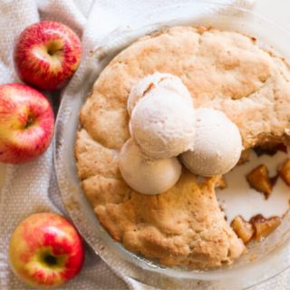 Apple cobbler topped with scoops of ice cream.