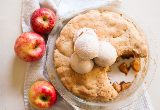 Apple cobbler topped with scoops of ice cream.