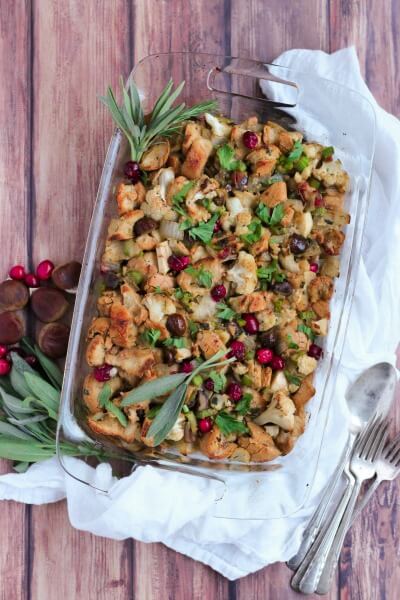 Casserole dish full of stuffing with cranberries and fresh sage.