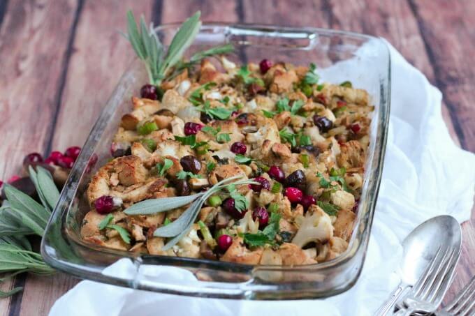 Casserole dish full of stuffing, cranberries and fresh sage.