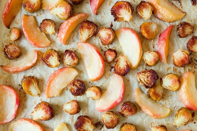 Roasted Brussels sprouts and apples on a baking sheet.