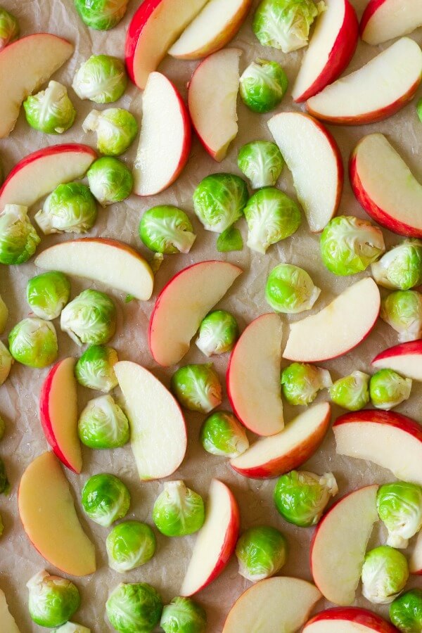 Brussels sprouts and apples on a baking sheet.