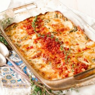 Scalloped potato casserole with bacon and thyme on top.